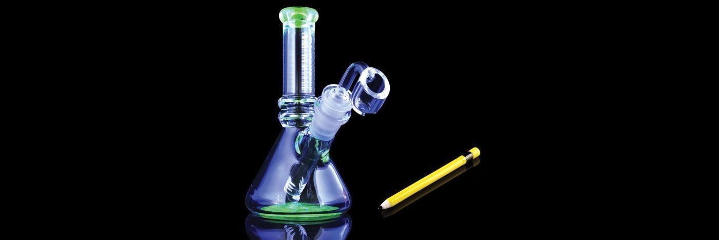 Glass bong on black background next to a pencil used to pull out a broken down stem