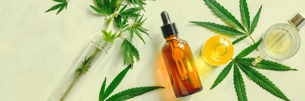 Various glass bottles with CBD oil, THC tincture and hemp leaves on a marble background