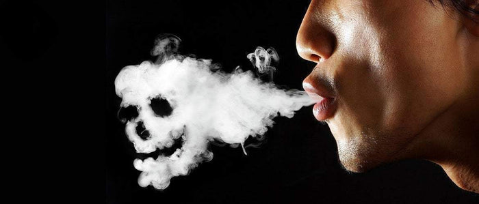 man blowing smoke cloud in the shape of a skull on a black background