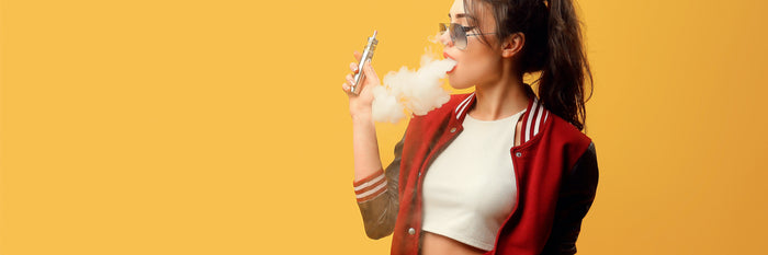 Attractive glamour woman standing and vaping on yellow background.