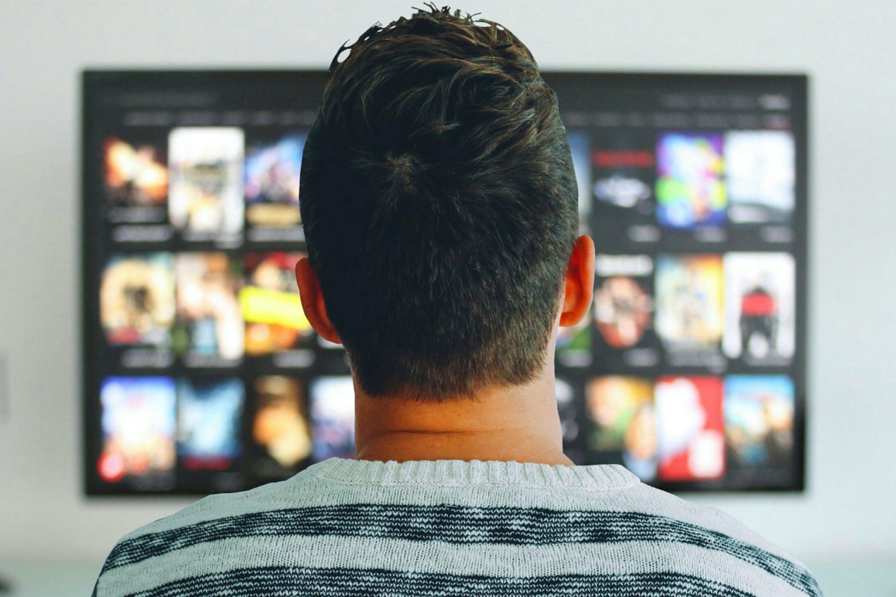 man watching TV with streaming services on the screen